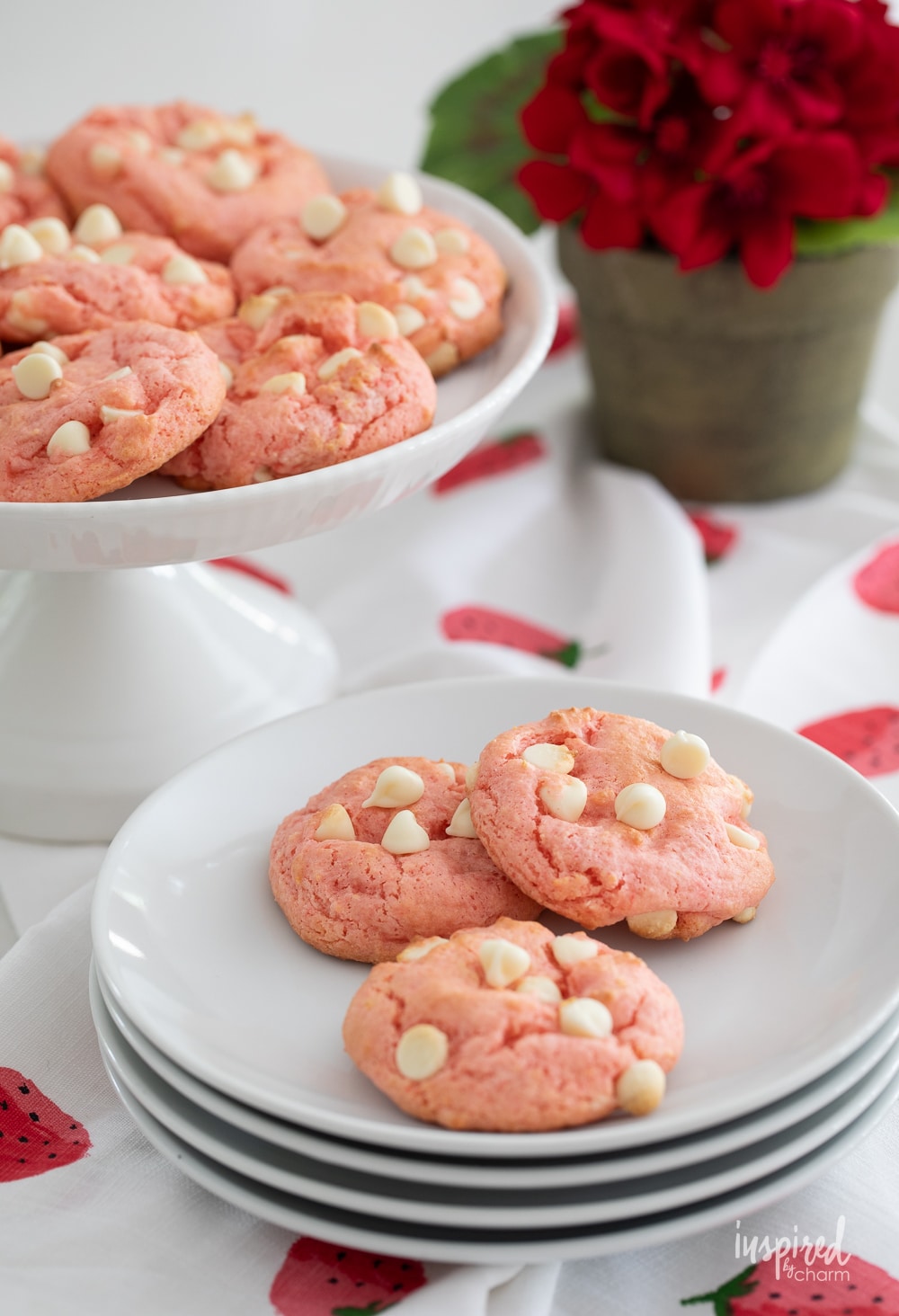 a small plate of three strawberry shortcake cookies with more in the background.