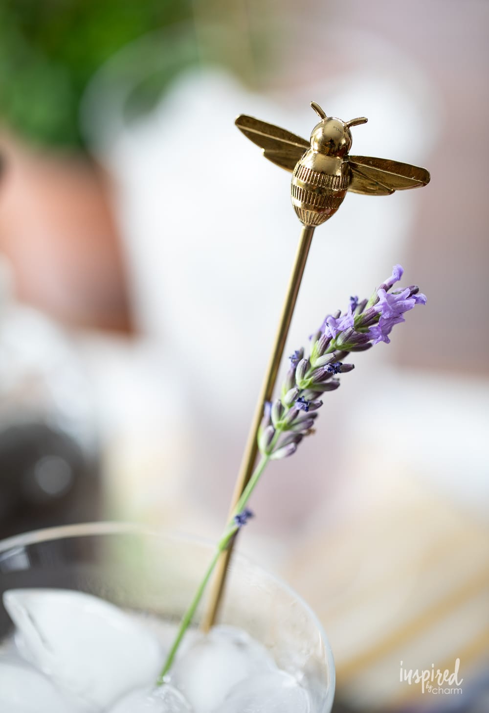 close up of a bee cocktail stirrer in a glass of lavender lemonade. 