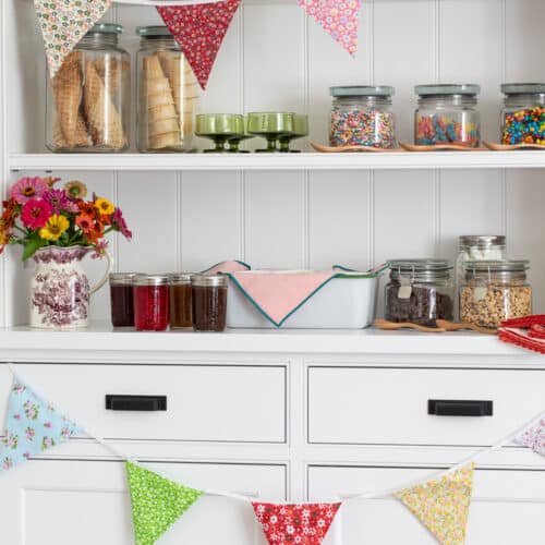 styled ice cream sundae bar with ice cream, toppings, cones, and festive decor.