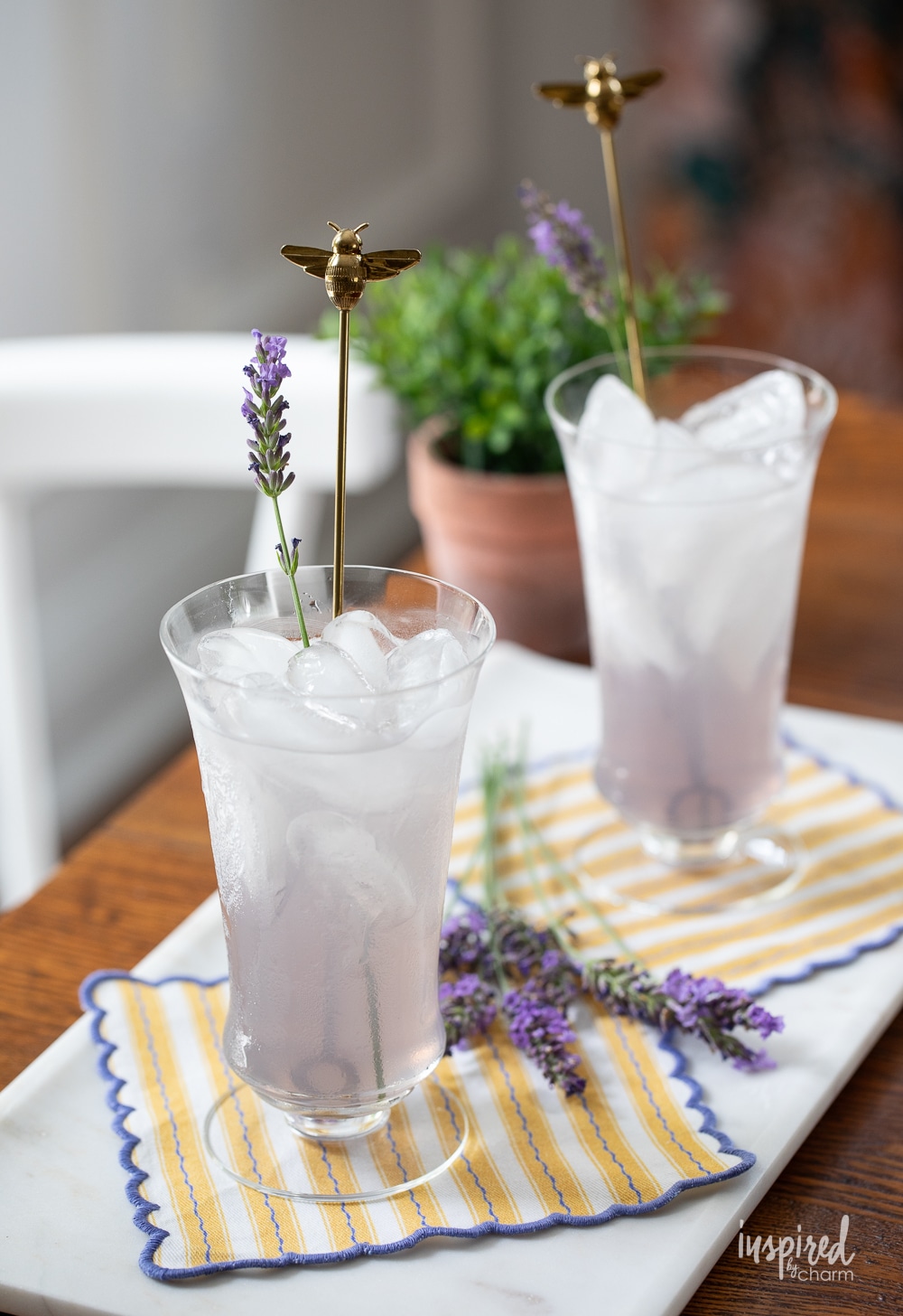 two glasses of lavender lemonade garnished with a piece of fresh lavender.