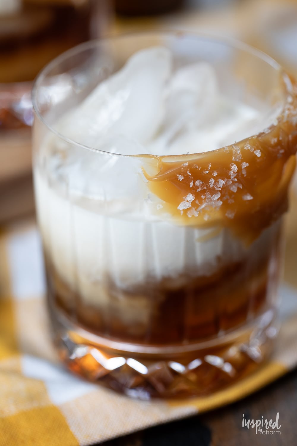 close up of butterscotch white russian in a rocks glass with butterscotch sauce garnish.