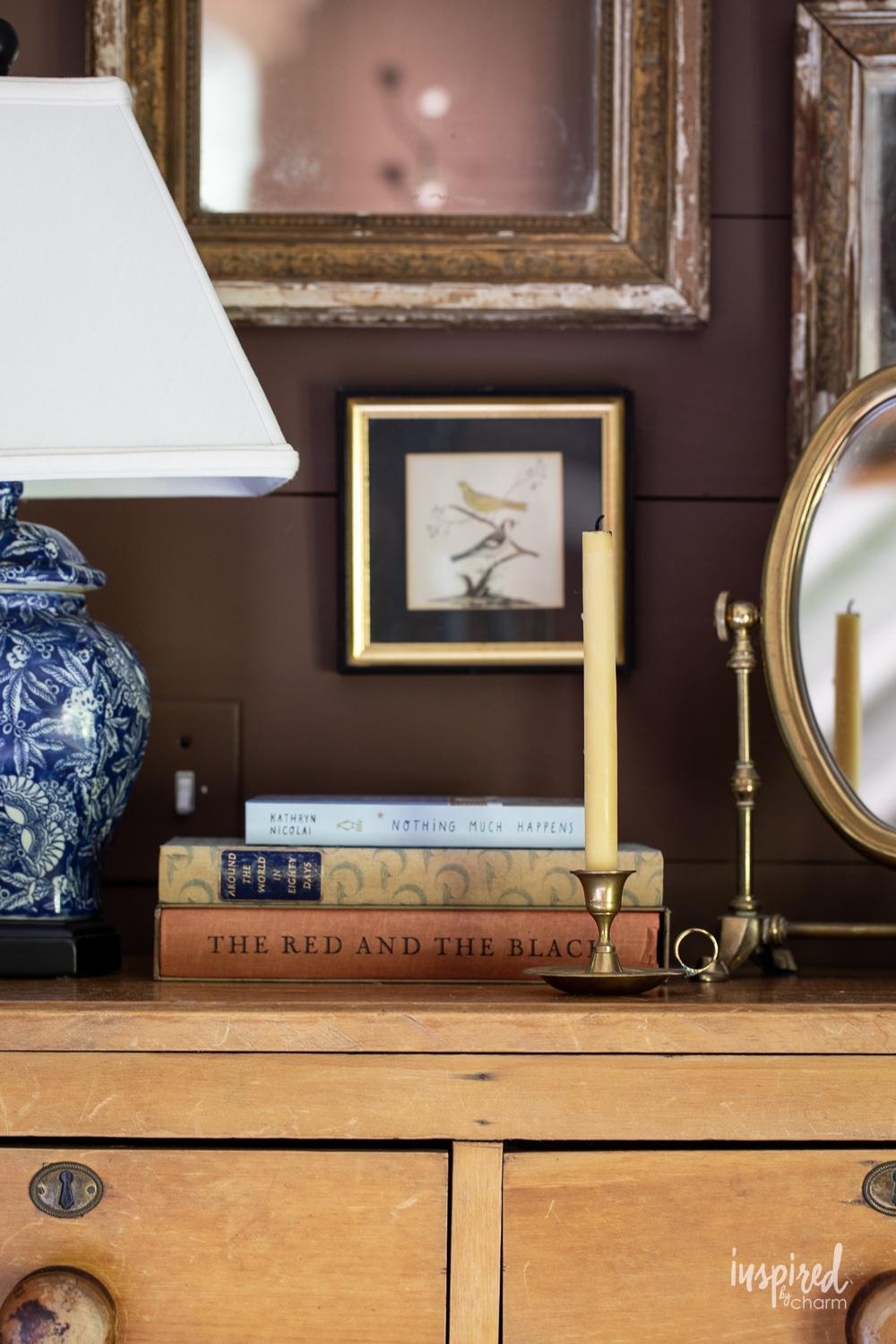close up of a night stand with vintage art, candlestick, and books. 