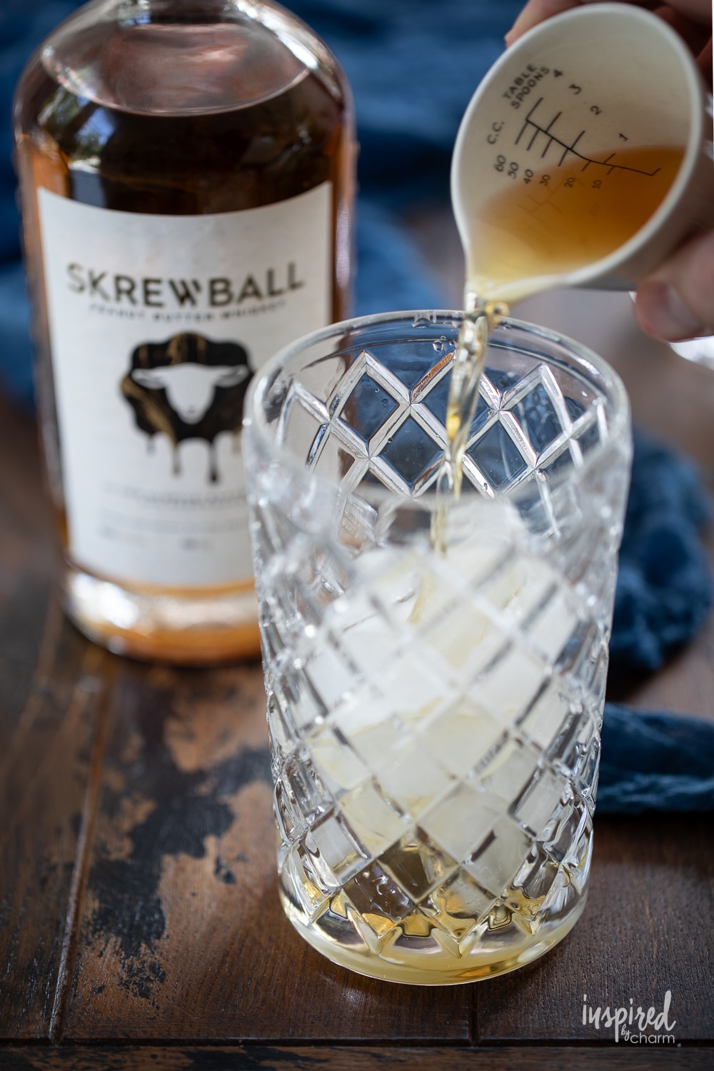 adding peanut butter whiskey to a glass with ice.