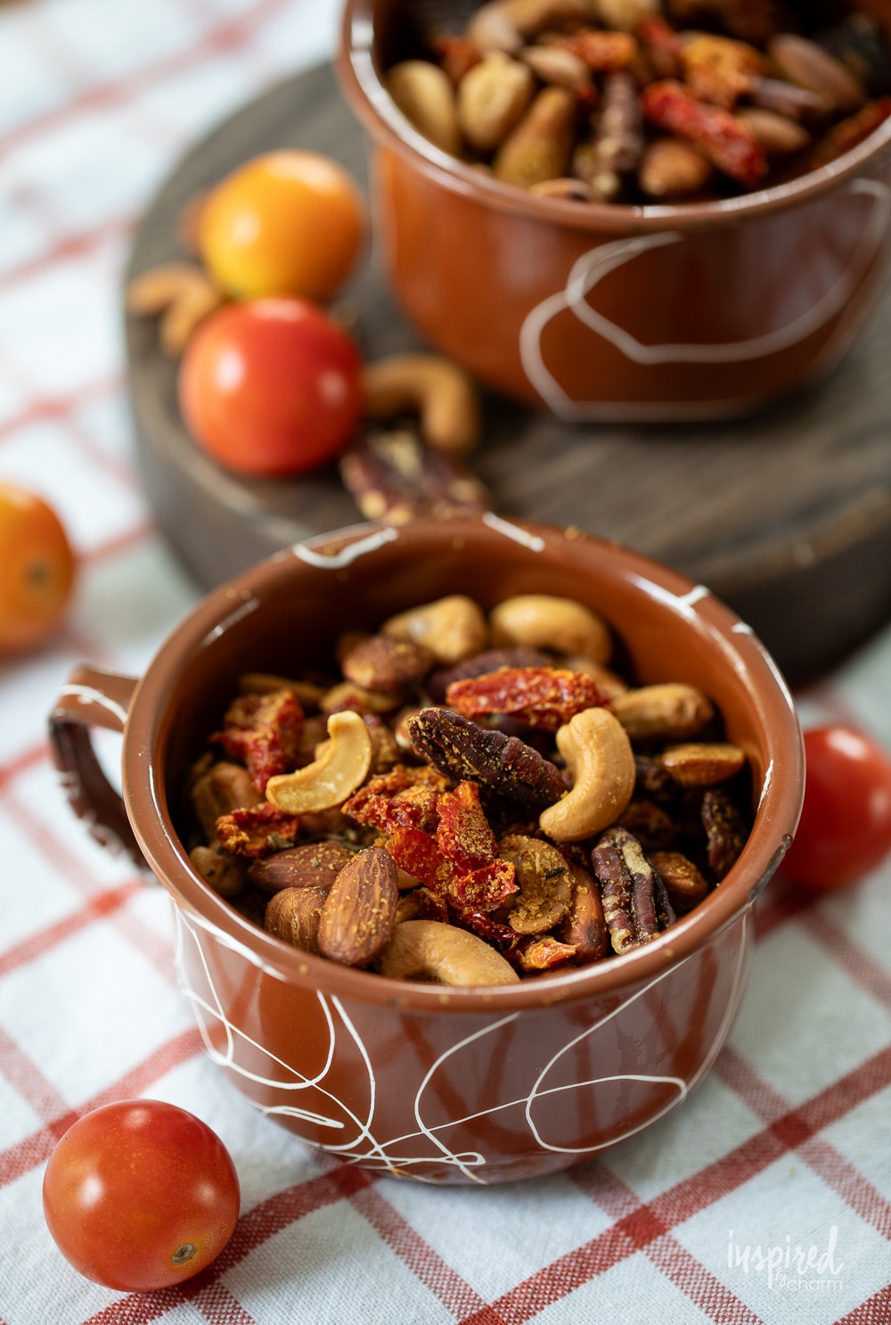 homemade pizza trail mix served in an enamel mug with cherry tomatoes.