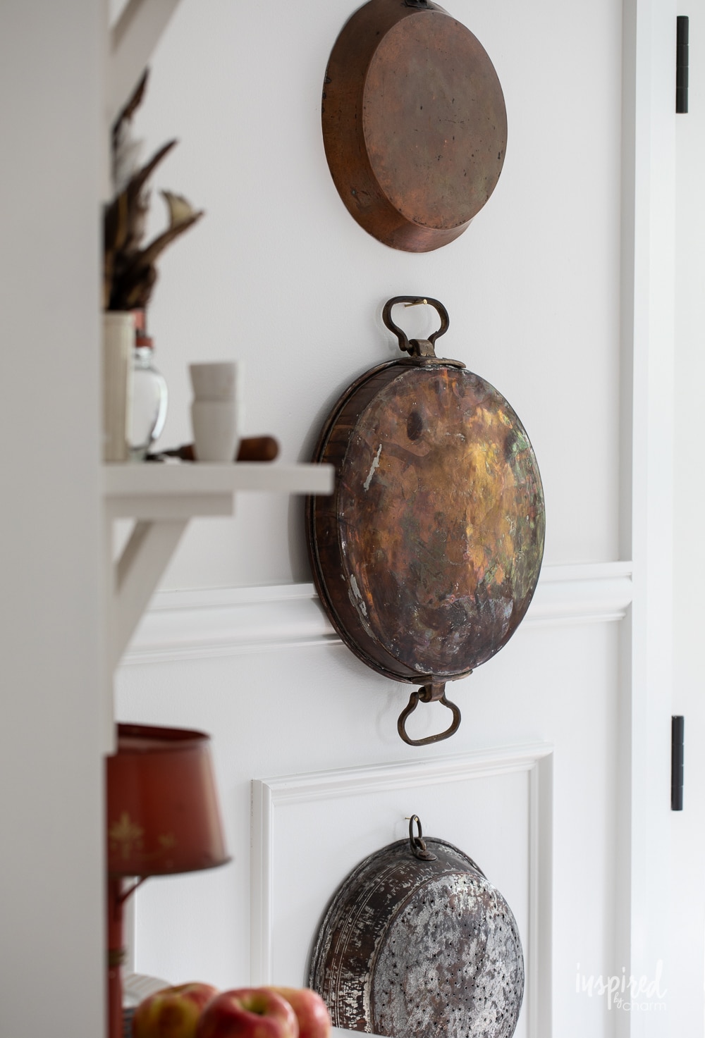vintage copper pots and pans hung on a wall. 