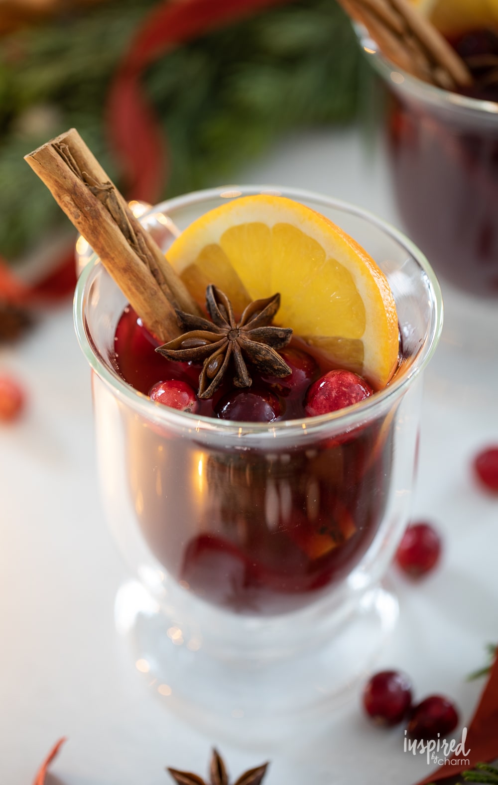 single spiced cranberry hot toddy served in a glass mug with orange slice and cinnamon stick. 