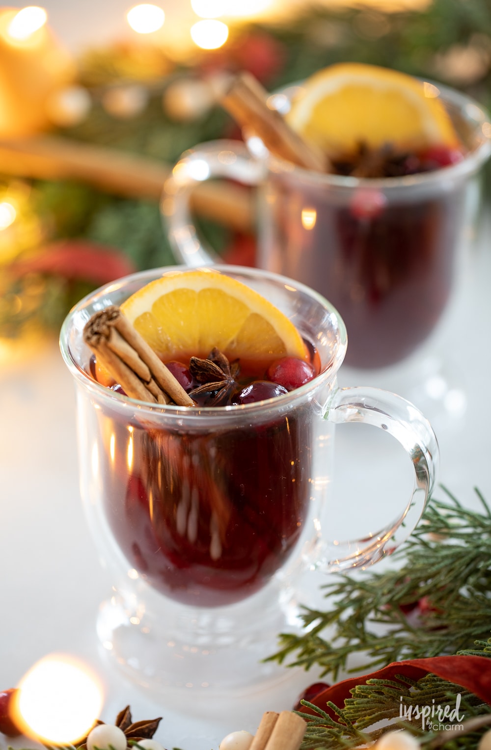 two spiced cranberry hot toddies in glass mugs. 