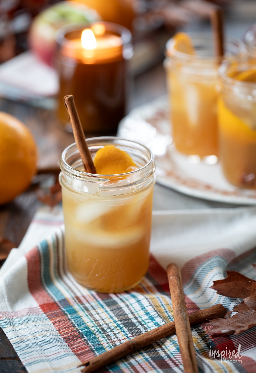 apple cider whiskey sour cocktail set in a cozy fall setting with a candle.