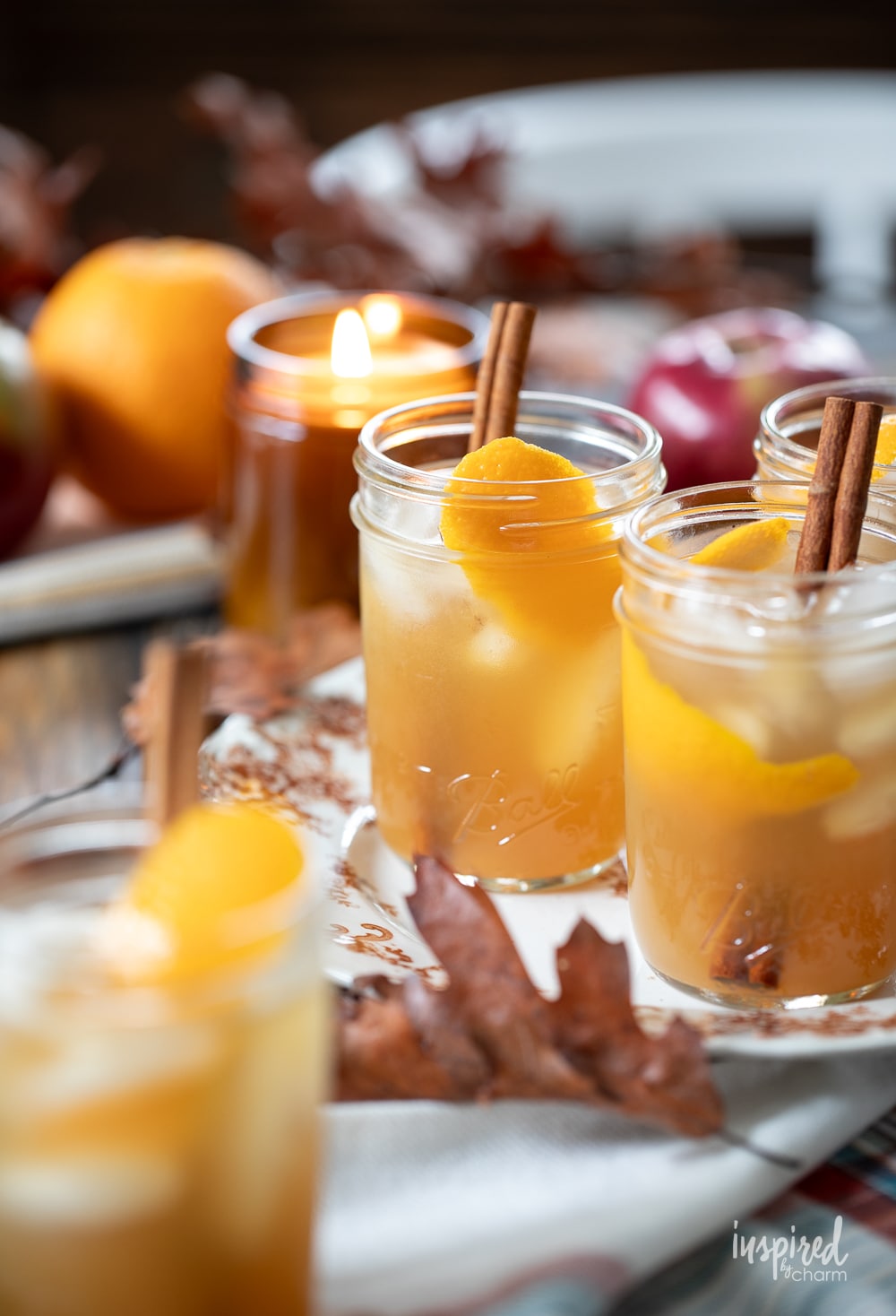 fall cocktails served in jars with cinnamon stick and orange peel slice. 