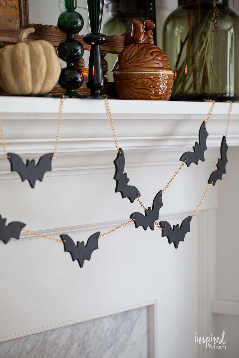 diy bat garland with black bats and gold chain on a white mantel.