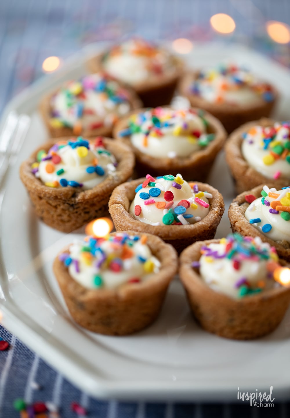 chocolate chip cookie cups filled with cheesecake and topped with sprinkles.