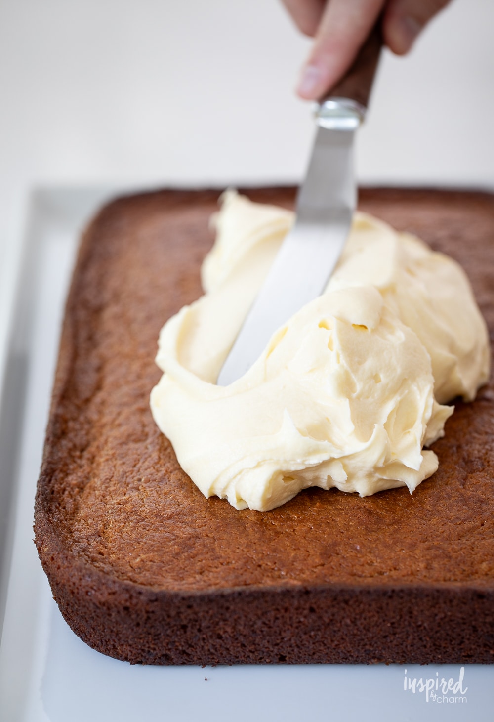 ofset spatula adding cream cheese frosting to the top of sweet potato cake. 