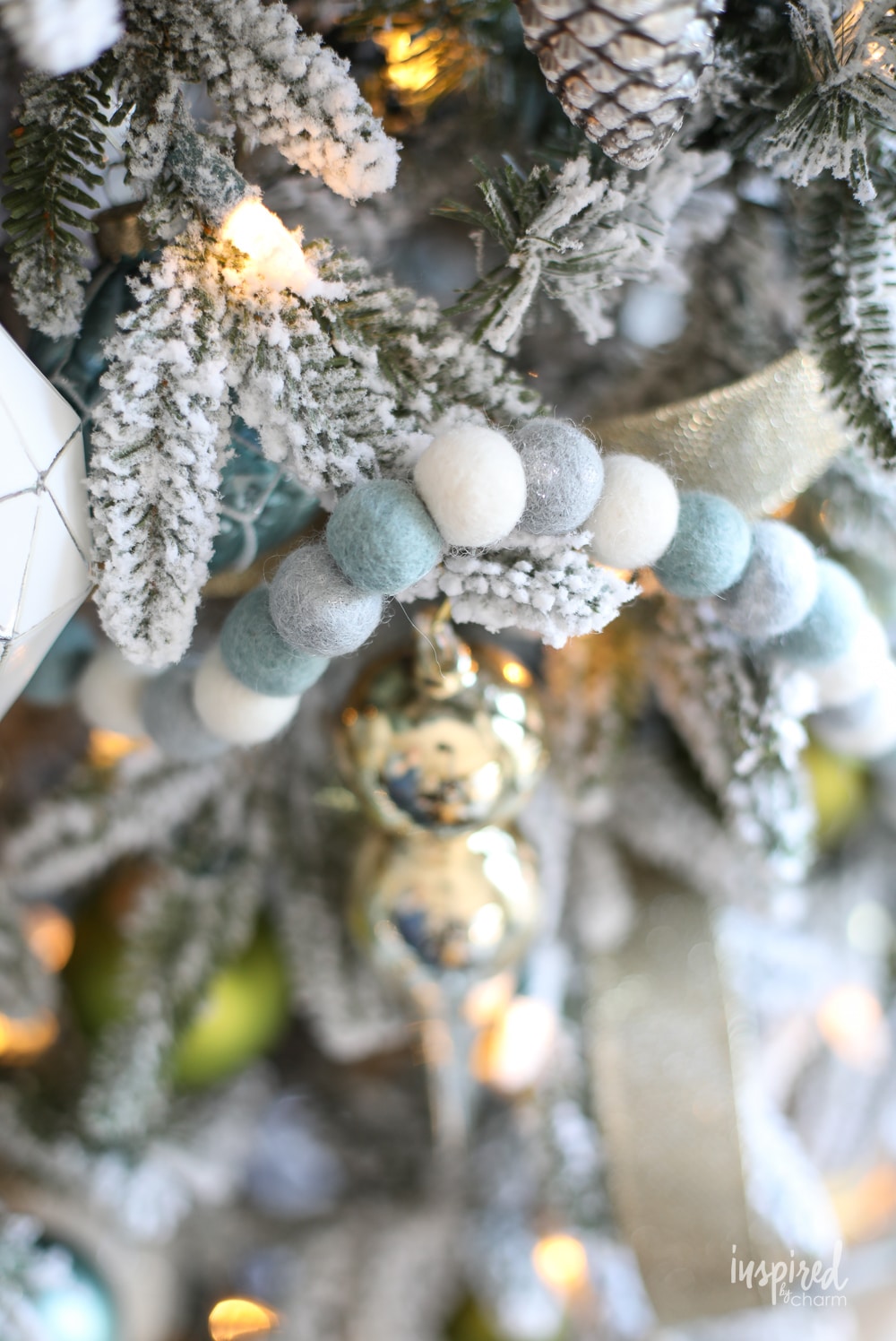 felt ball garland strung on a flocked christmas tree. 