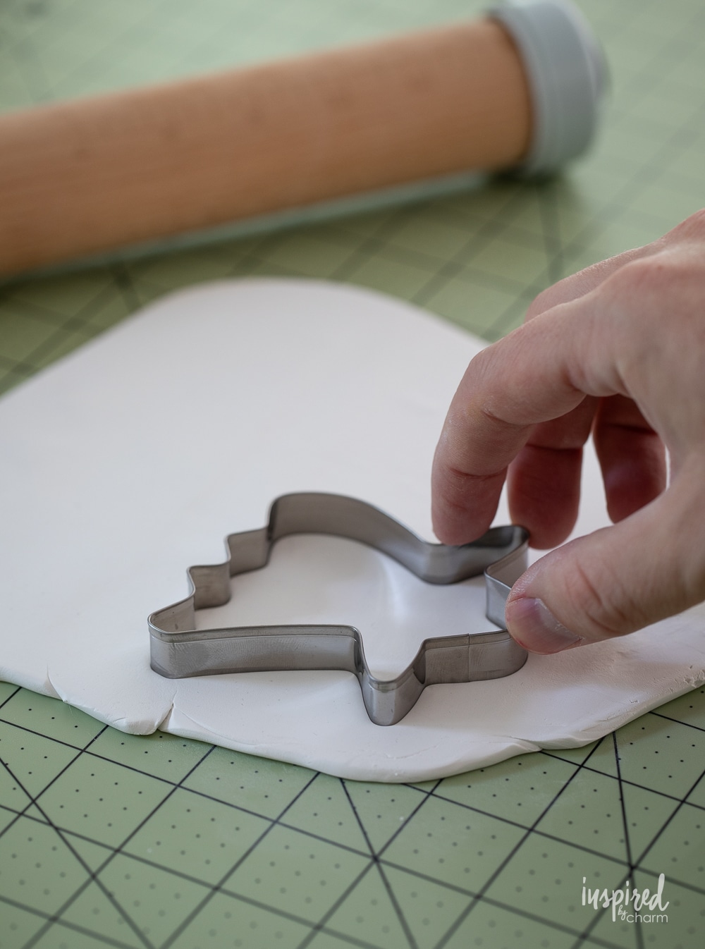 hand using a ghost cookie cutter to cut out clay.