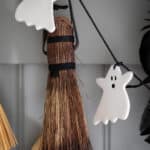 up close image of ghost garland hung on hooks in front of brooms.