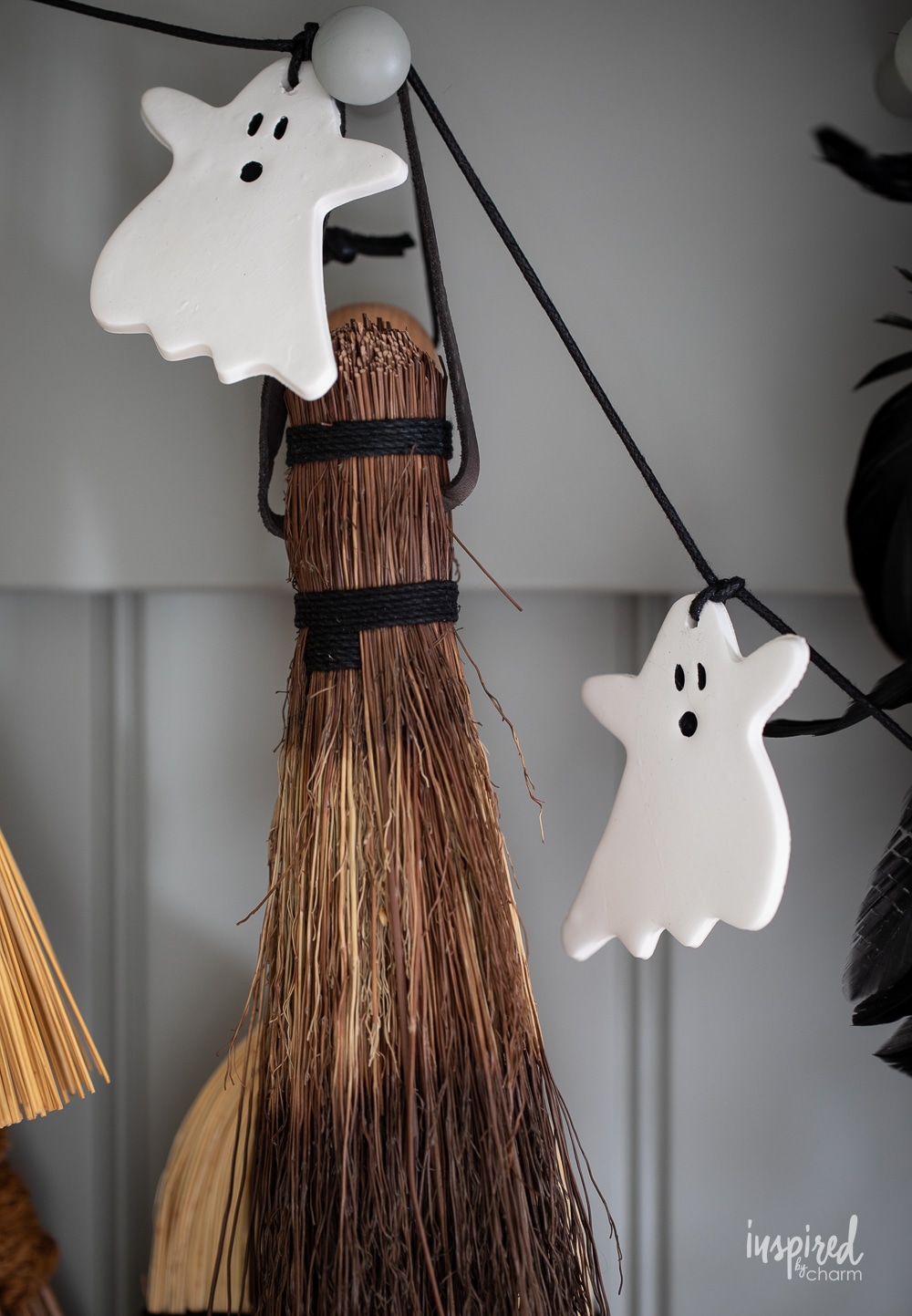 up close image of ghost garland hung on hooks in front of brooms.