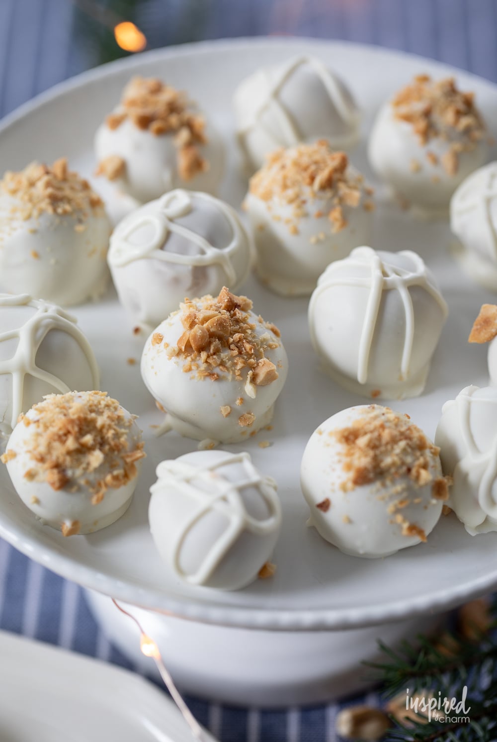 white chocolate covered peanut butter truffles on a white cake stand.