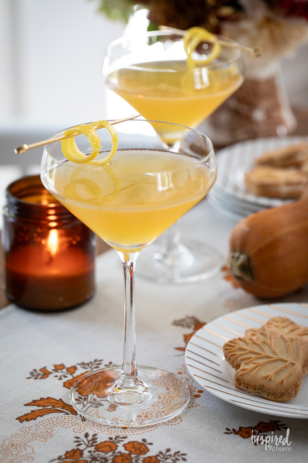 two maple martinis in glass surrounded by fall decor. 