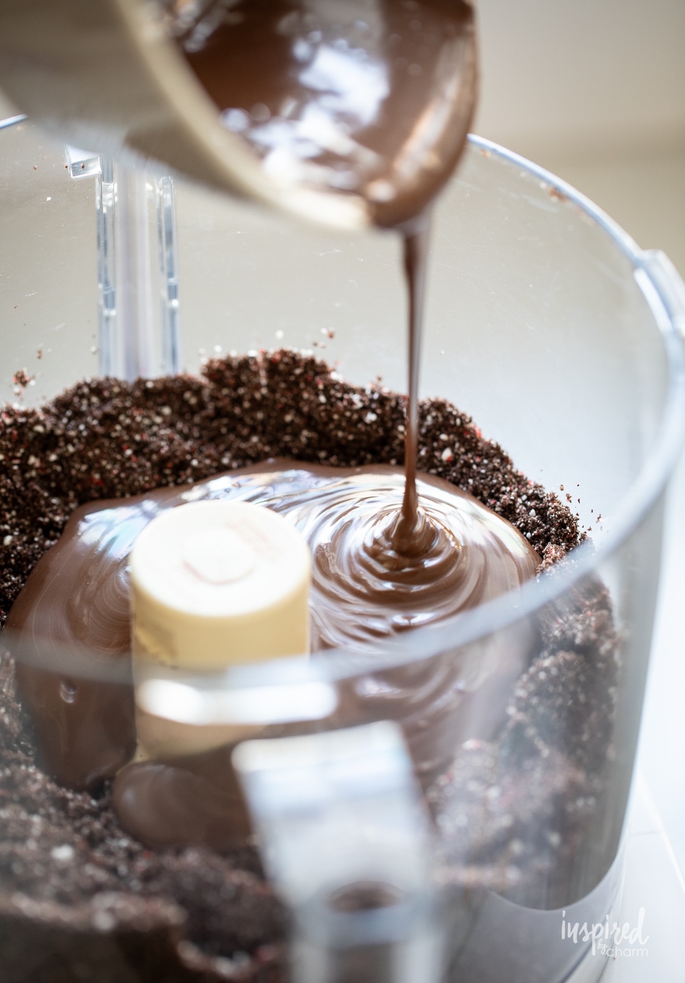 pouring chocolate into crushed Oreos in a food processor. 