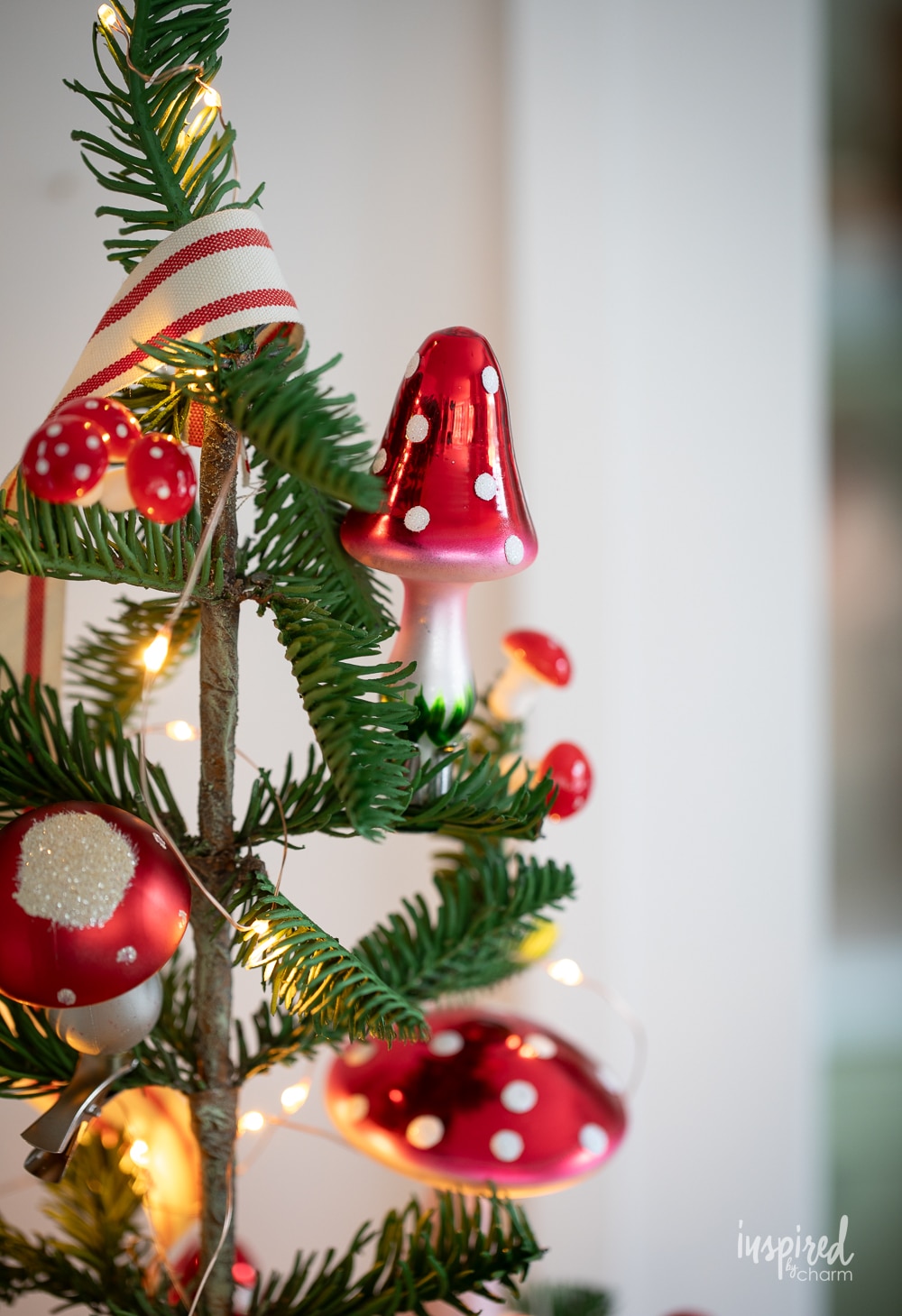 glass mushroom christmas ornament clipped onto a christmas tree.