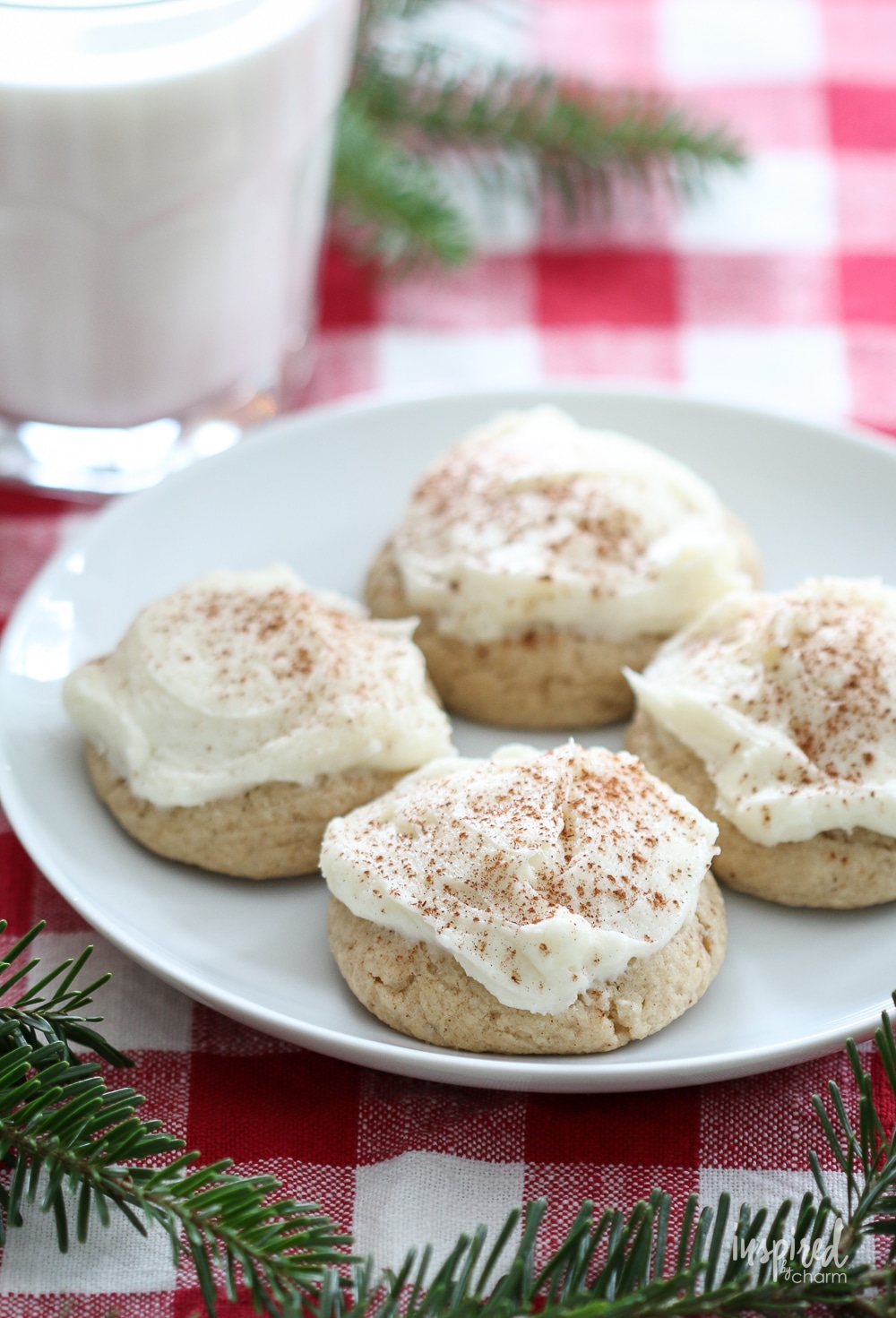 frosted eggnog christmas cookies on a plate with a glass of milk.