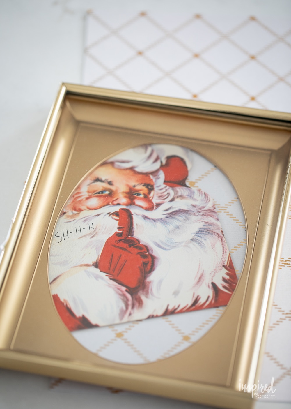 putting a christmas card of santa into a gold frame.