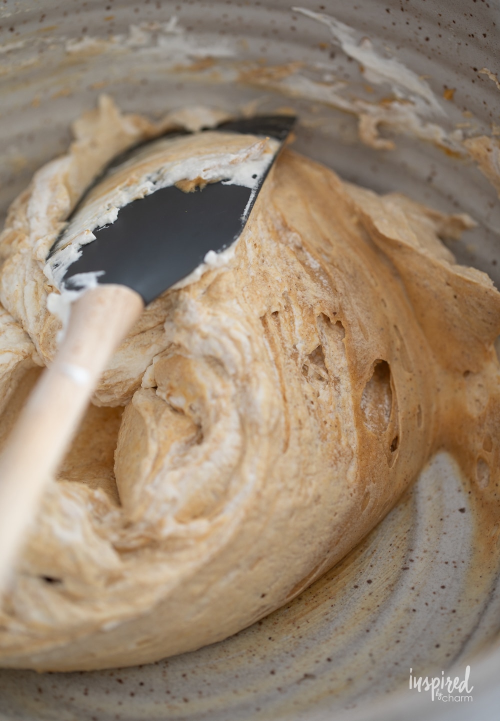 mixing whipped cream into gingerbread dip with a spatula. 