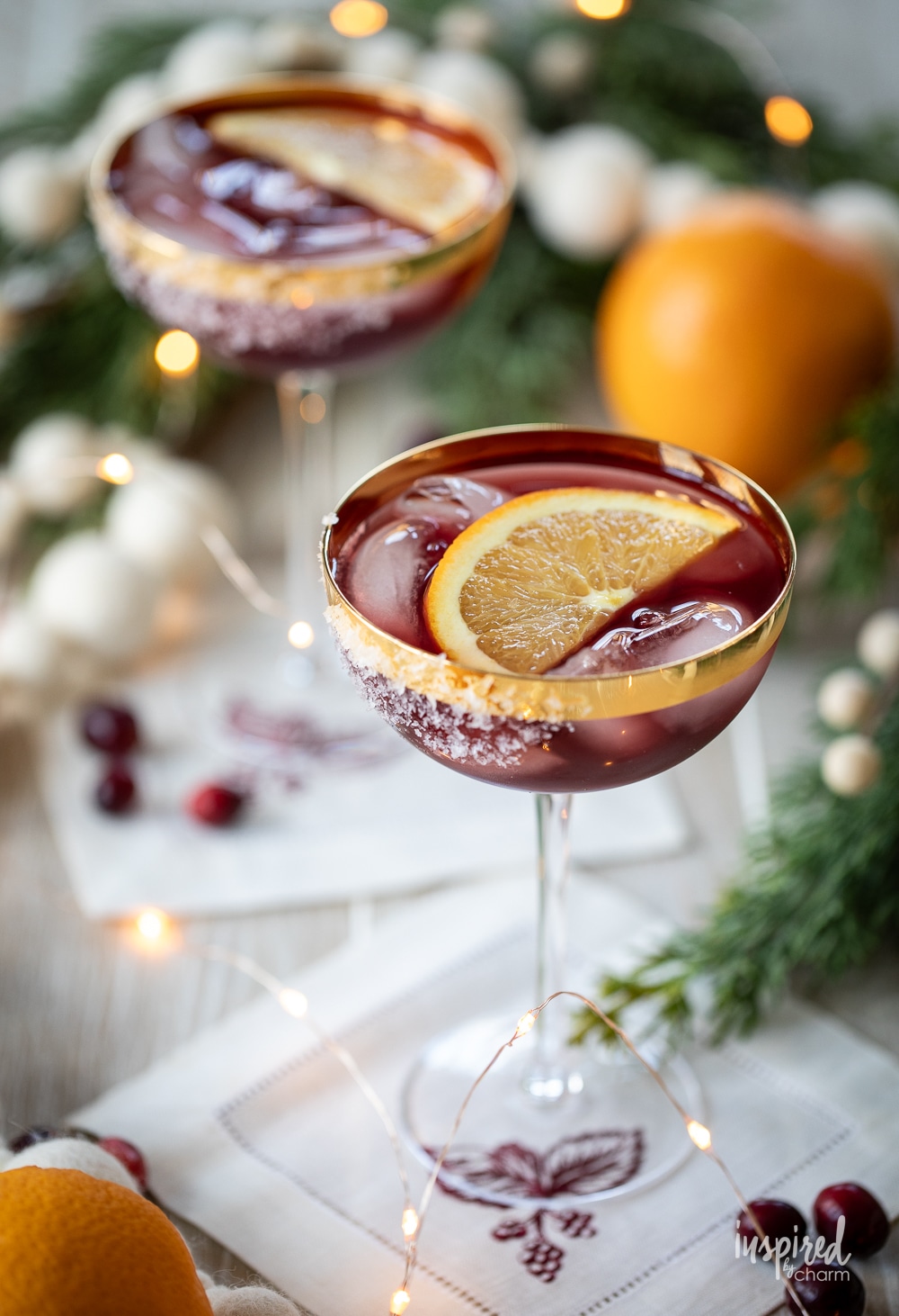 two mulled wine margaritas in coupe glasses in a festive setting. 