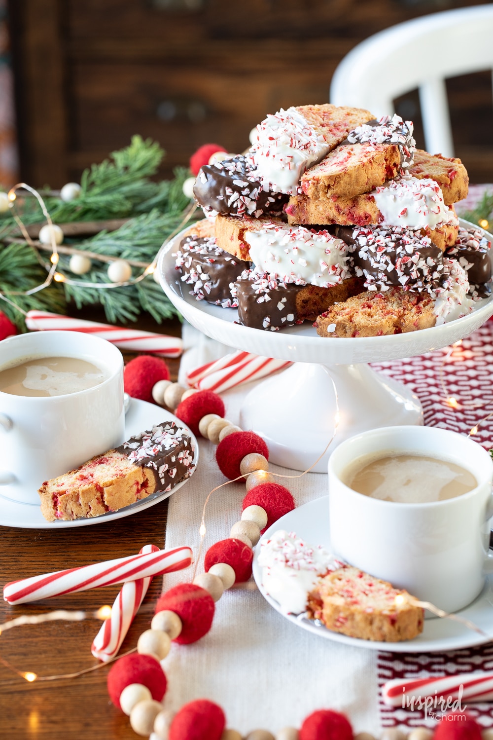 peppermint biscotti on a cake stand with cups of coffee.