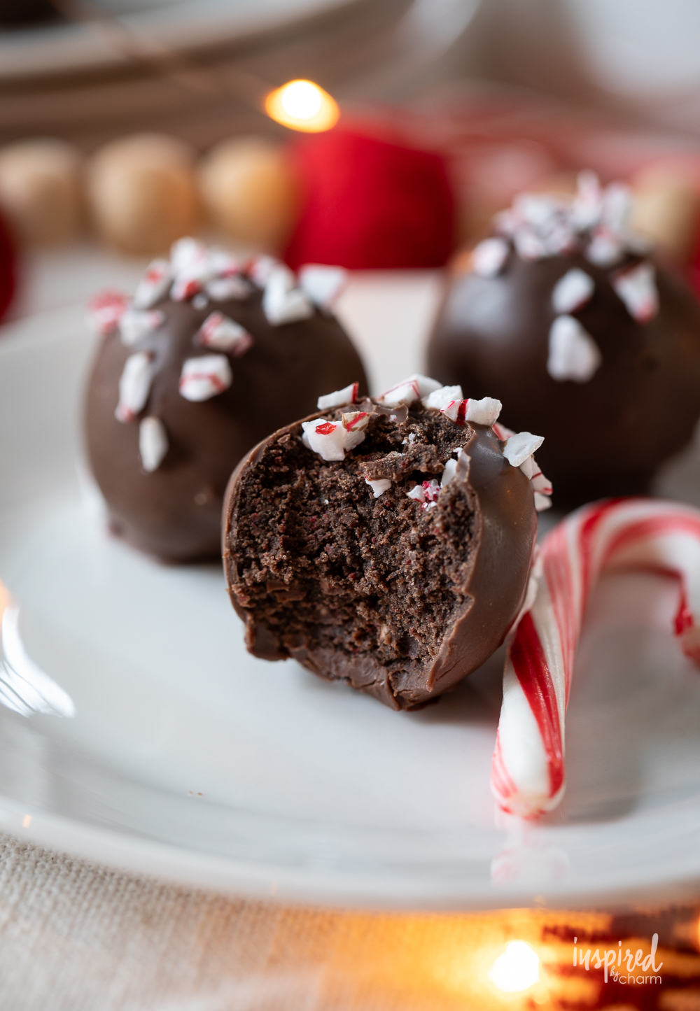 three peppermint Oreo truffles with a bite taken out of one.