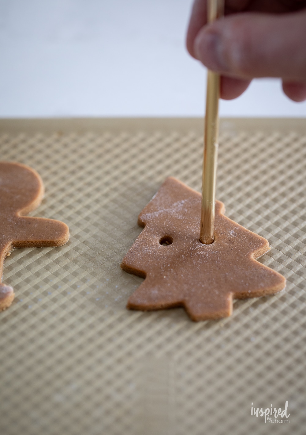 hand with metal straw adding holes to cookies.