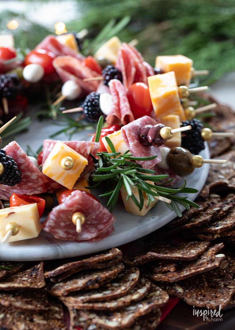 antipasto skewers on plate garnished with rosemary and crackers.