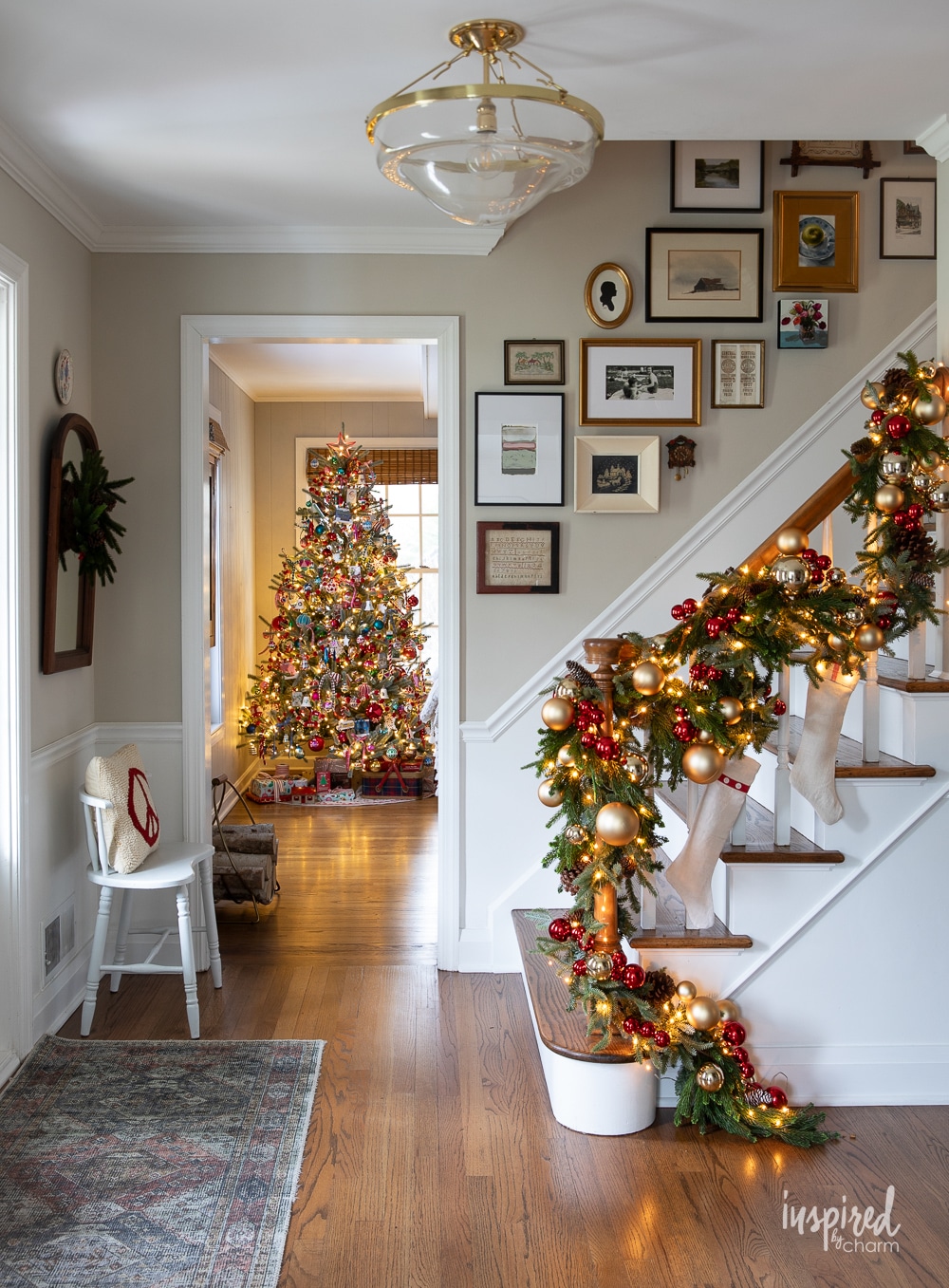 entryway with banister garland and christmas tree in the background. 