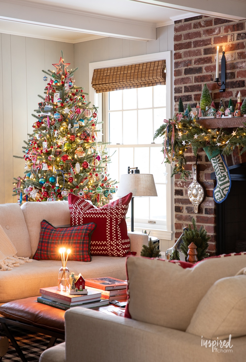 living room with sofa, pillow, brick fireplace and colorfully decorated christmas tree.