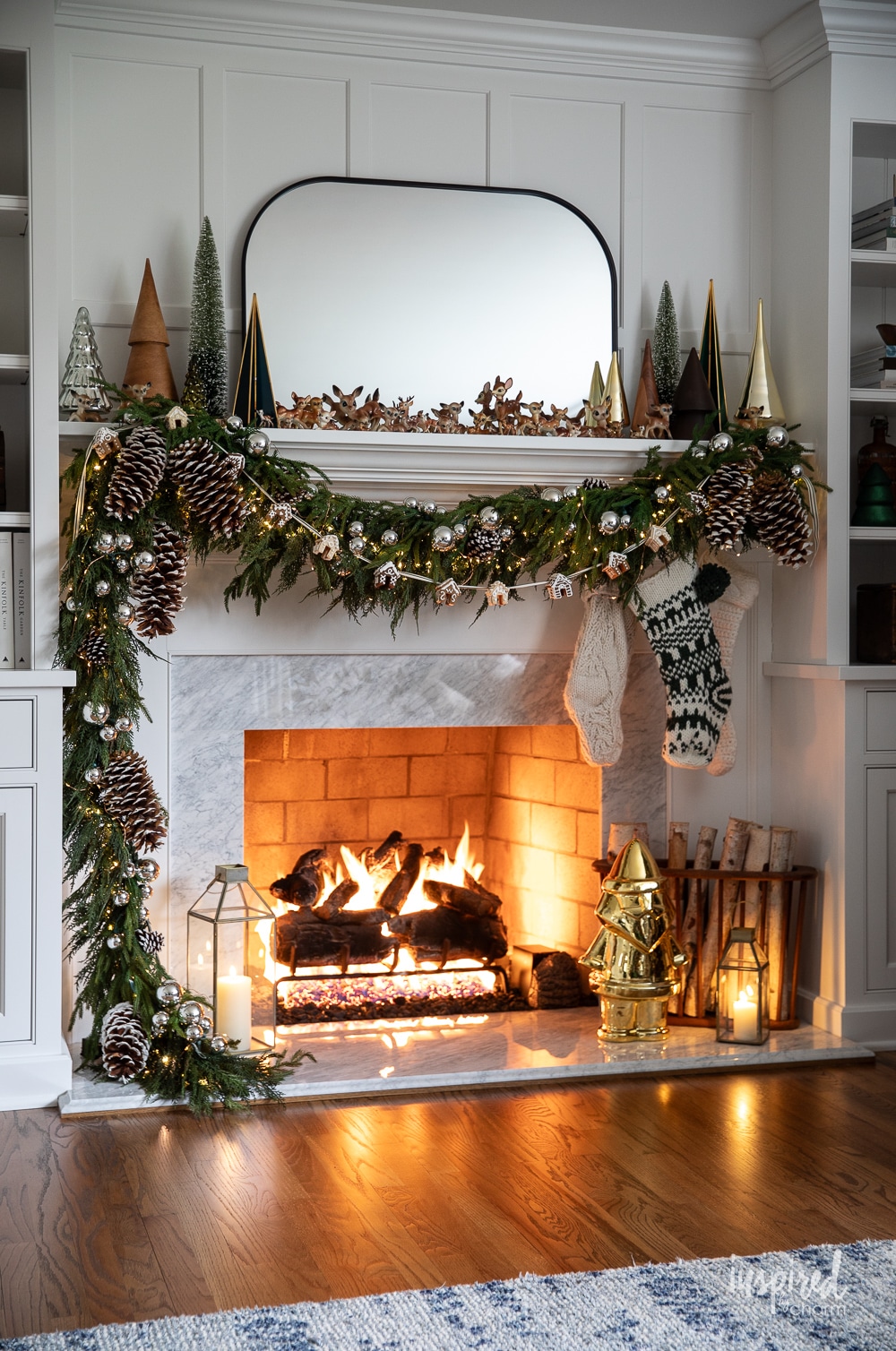 mantel decorated for christmas with garland, stocking, and lit fire. 