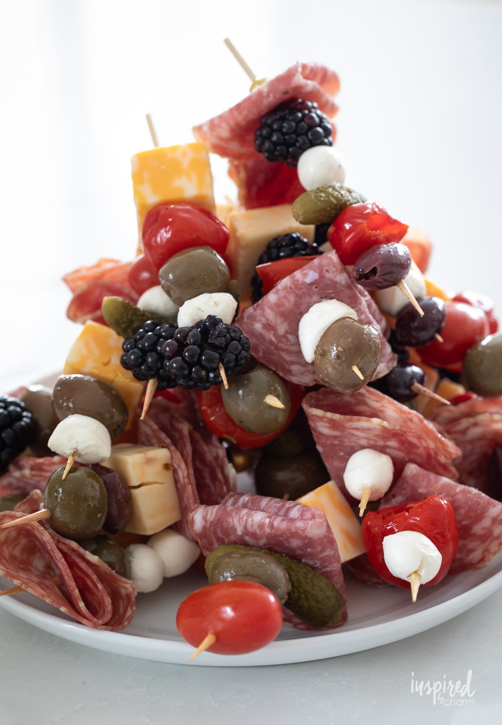 plate filled with antipasto skewers stacked together.