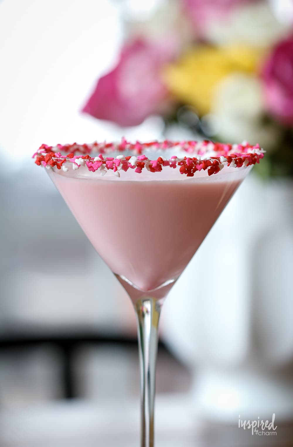 Valentine's Day cocktail in martini glass with heart sprinkles.
