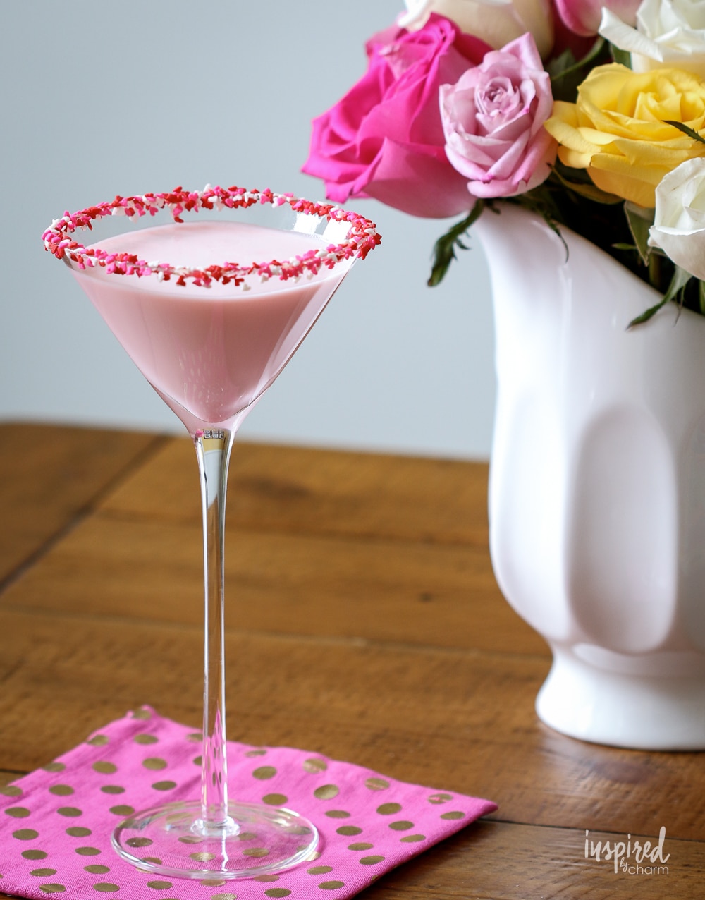 Valentine's Day martini in front of white pitcher with roses. 