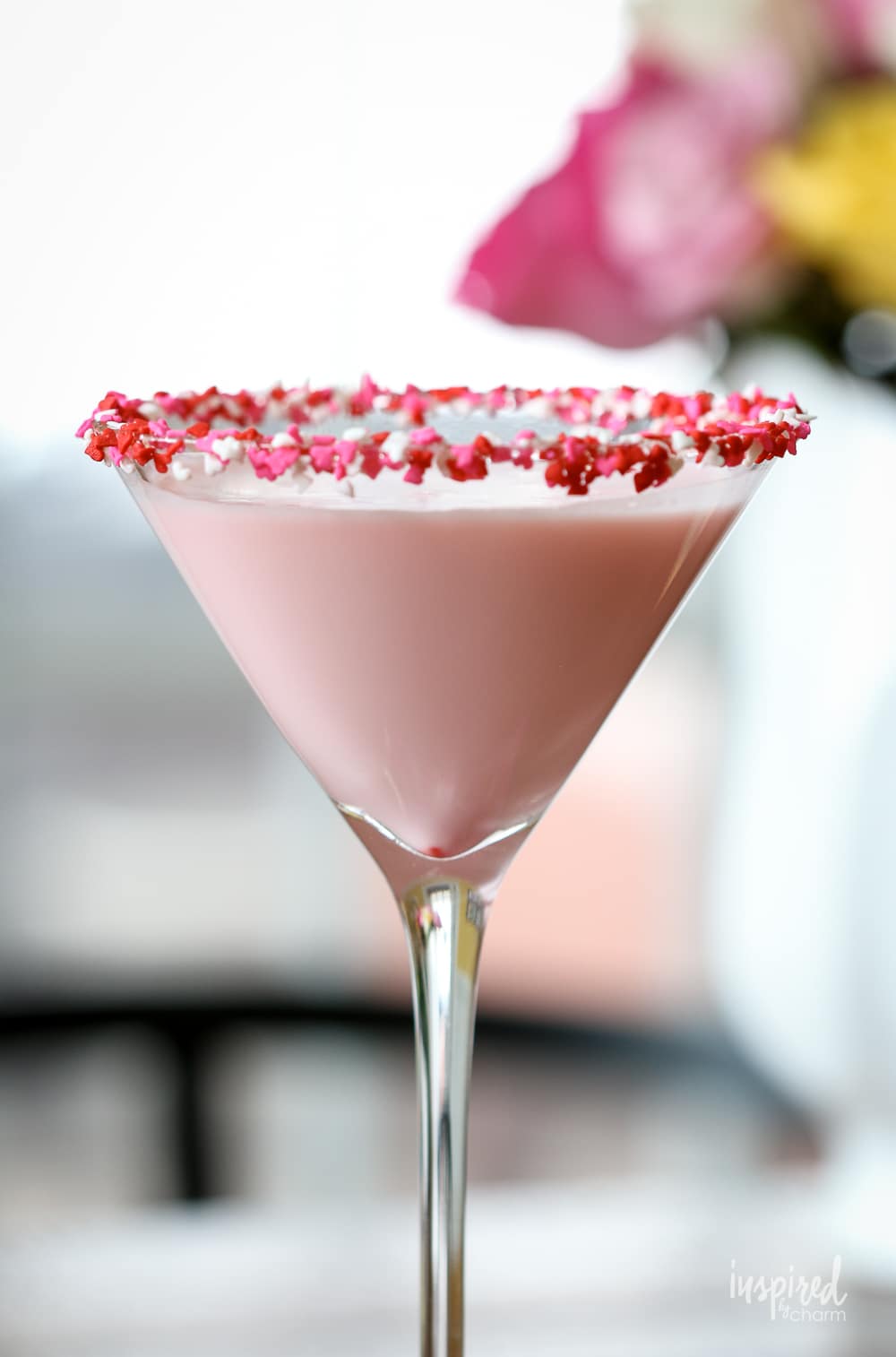 pink cocktail for Valentine's Day in martini glass with sprinkle garnish.