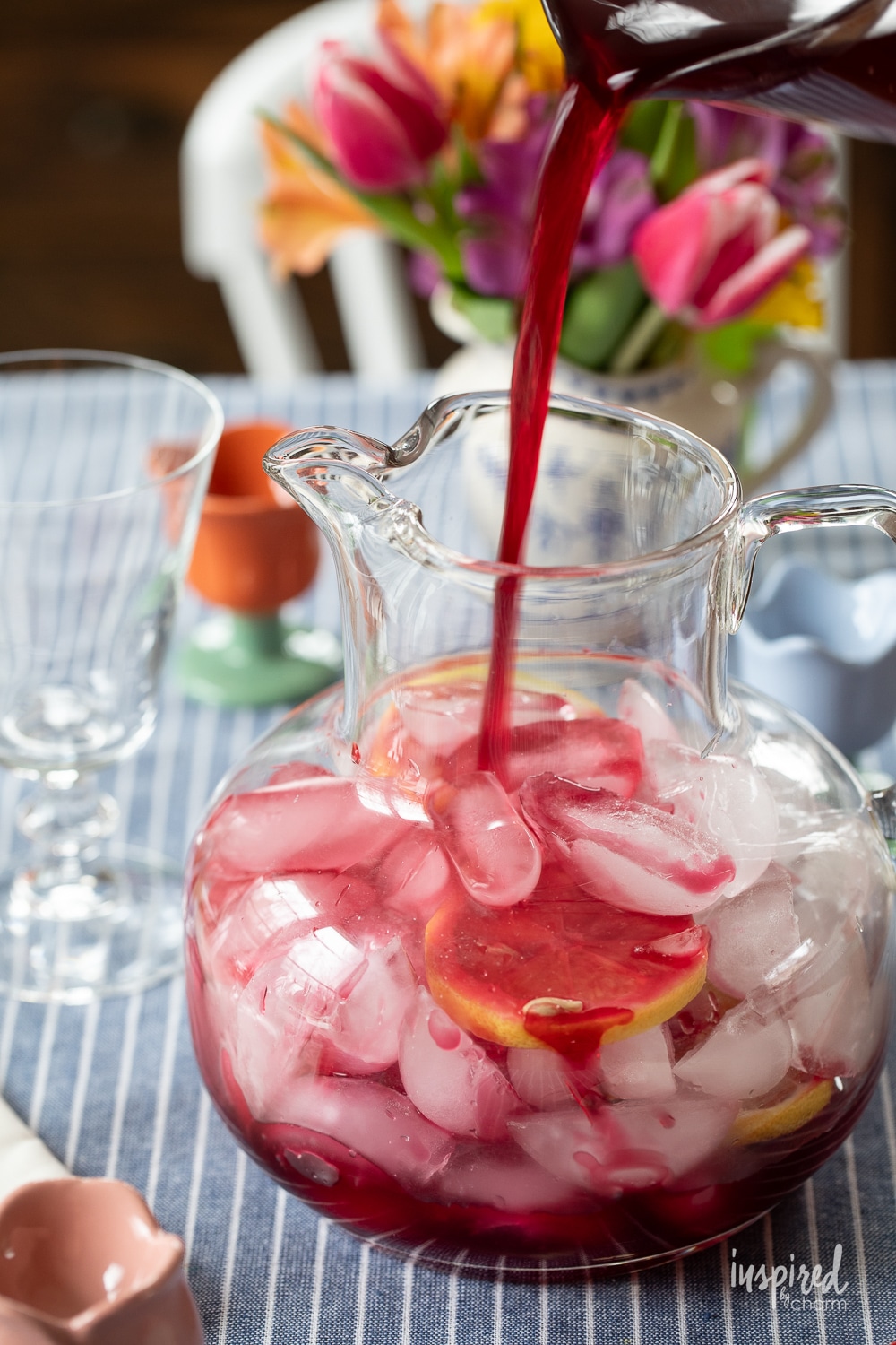 pouring cranberry juice into a pitcher with ice. 