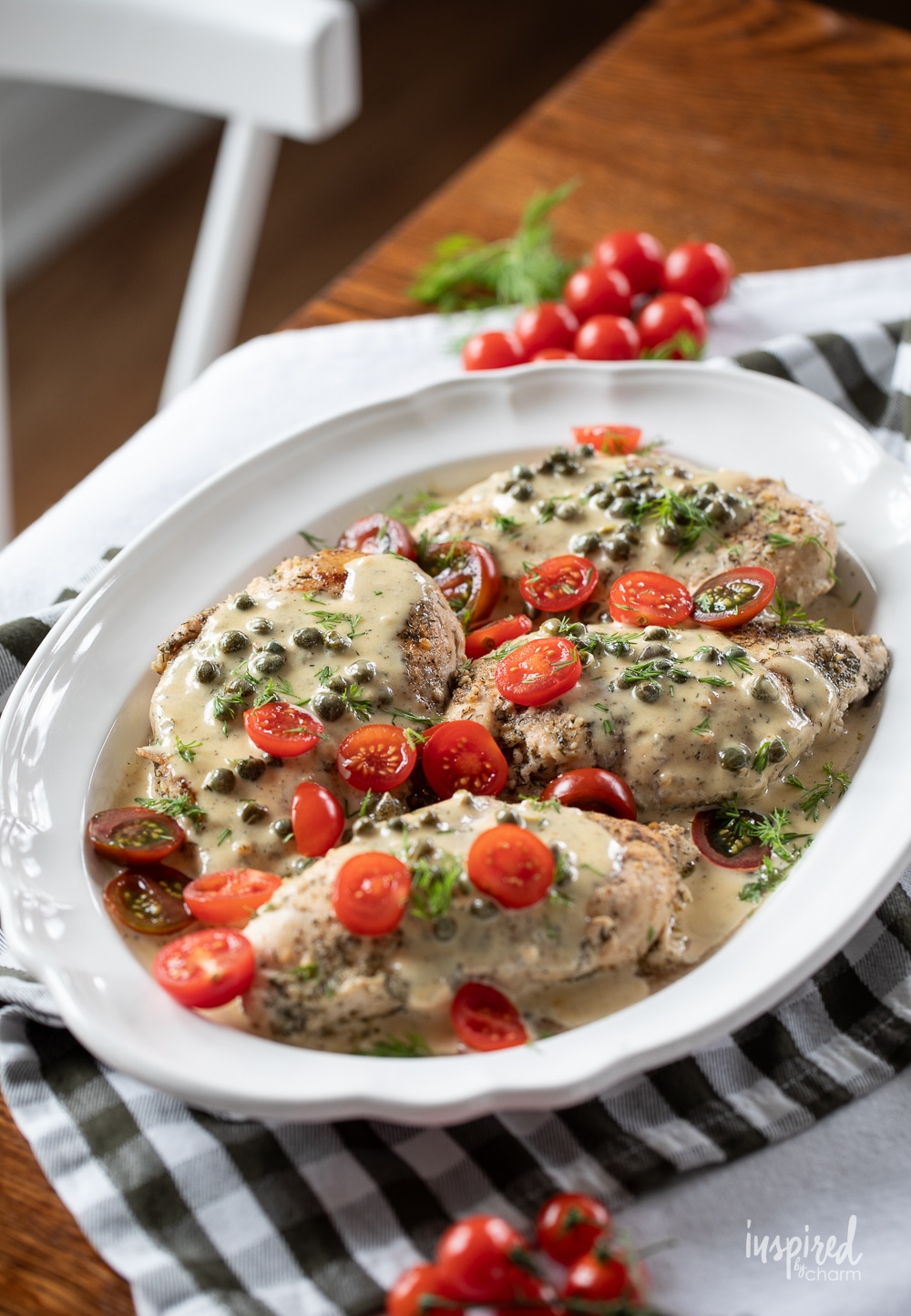 platter filled with chicken breast drizzled with caper cream sauce.
