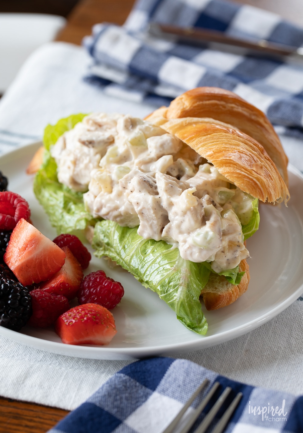 chicken salad sandwich served with fruit on a plate.