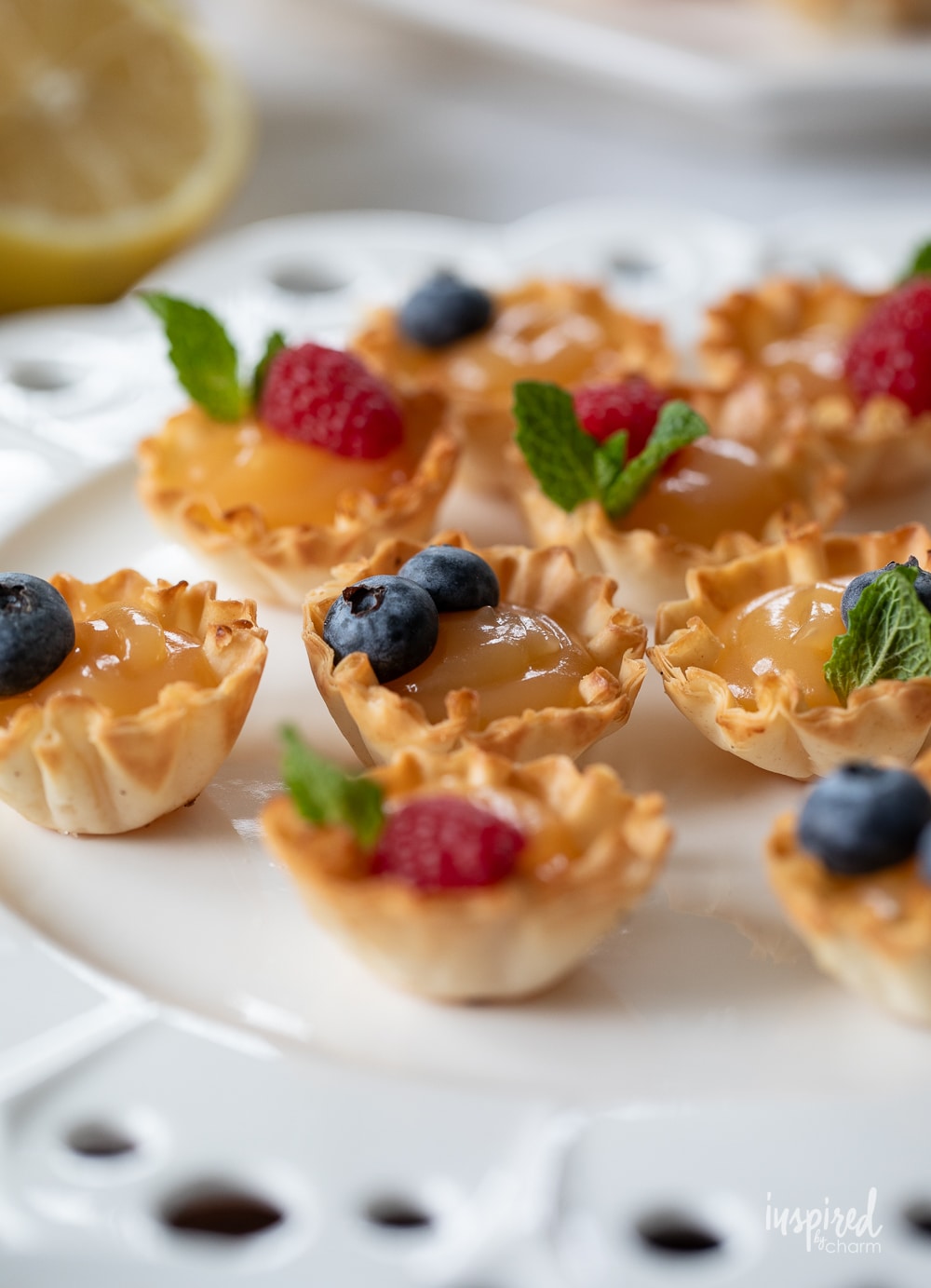 small lemon tarts topped with berries on a plate. 