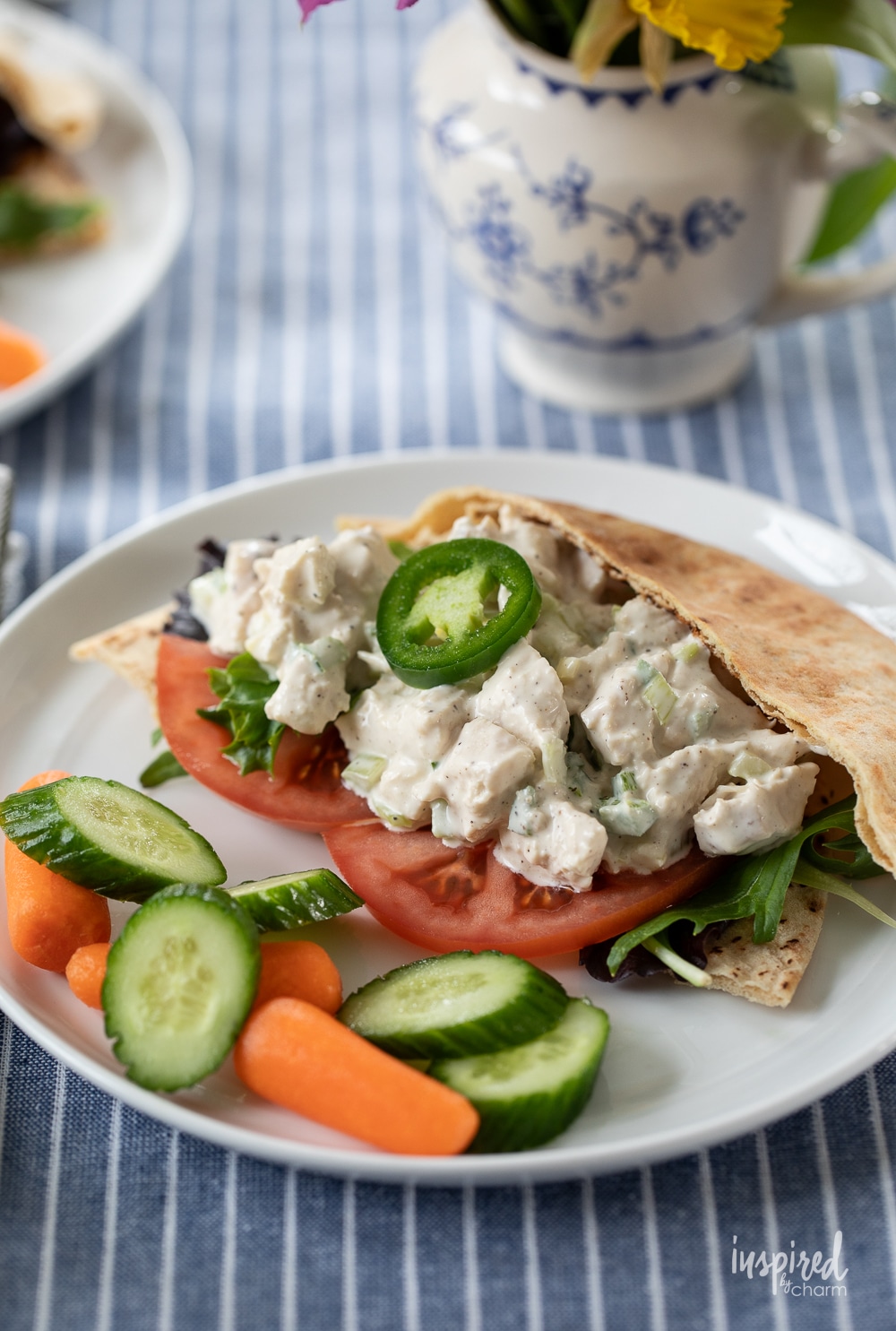 Jalapeño Honey Chicken Salad served in a pita on a plate with vegetables. 