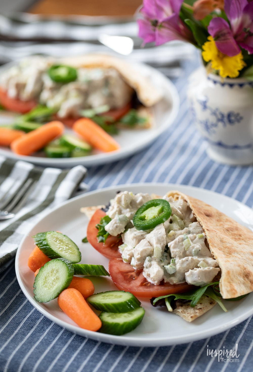 two plates with Jalapeño Honey Chicken Salad served in pitas. 
