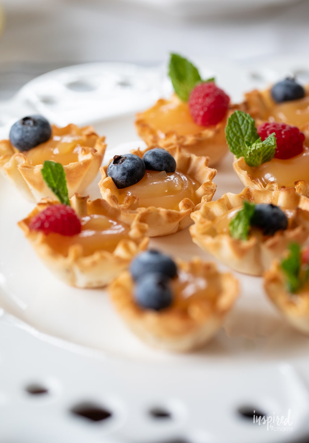 adorable mini lemon tarts garnished with mint and fresh berries. 