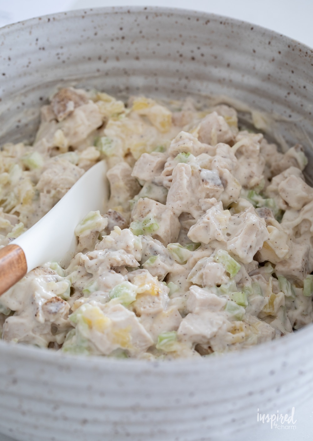 mixed chicken salad in a bowl with a spatula.