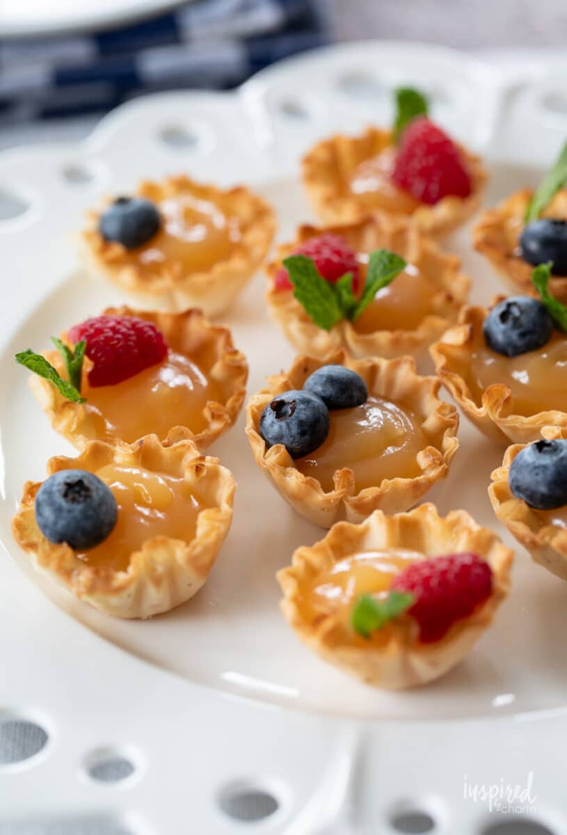 lemon curd tartlets with fresh berries on a plate.