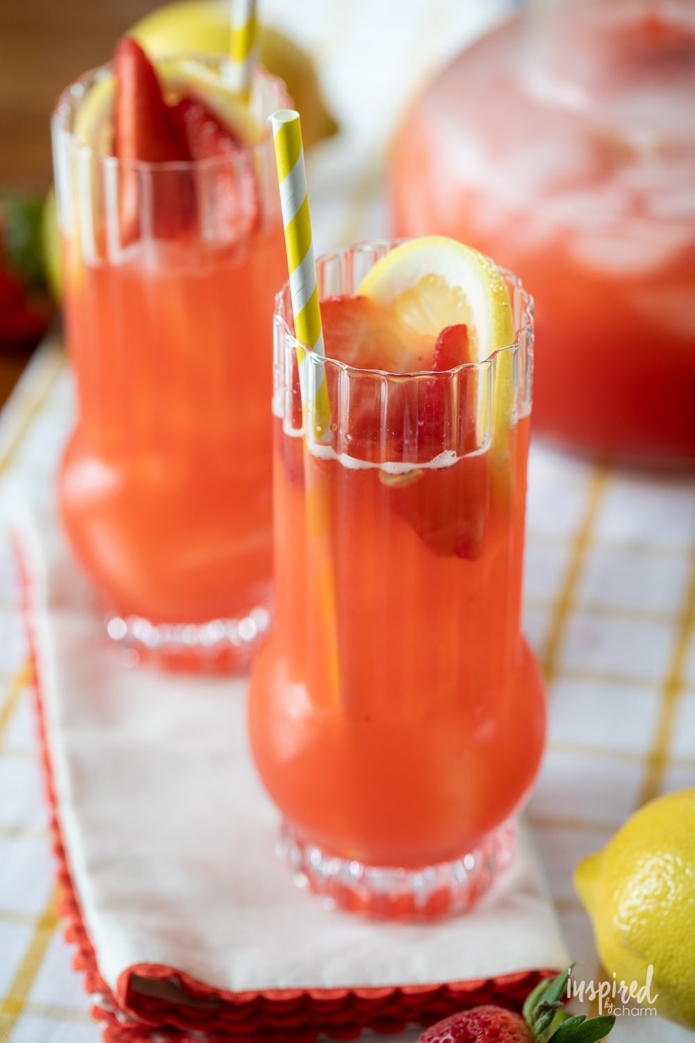 Strawberry Lemonade Vodka Cocktails in glasses with paper straw and strawberries and lemons.