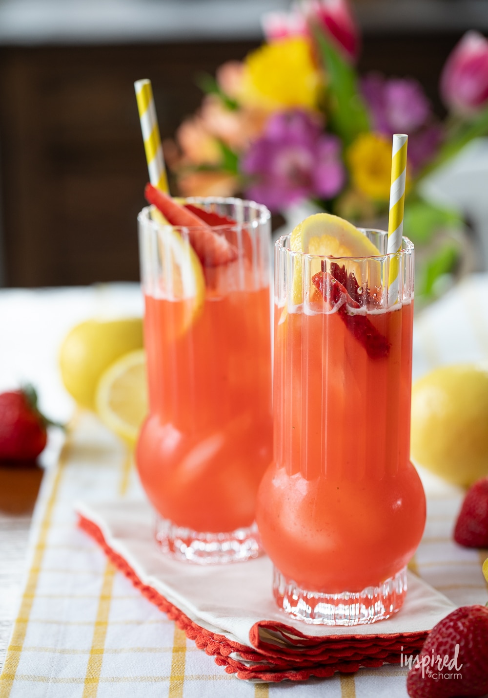 Two Strawberry Lemonade Vodka Cocktail Drinks on a table with lemons and strawberries.